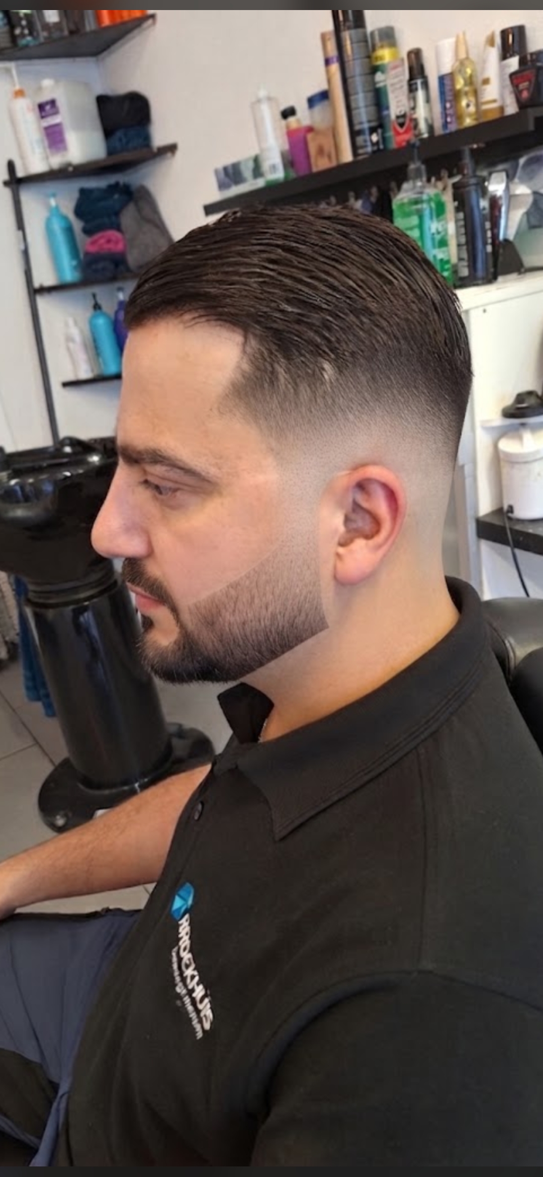 Klant met een strakke fade, van opzij gezien, in de stoel bij Salon Milan